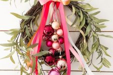 a catchy and bold Christmas wreath of vine, red, pink and gold ornaments, greenery and a matching ribbon bow