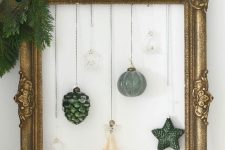 a chic Christmas wreath of a vintage frame, some evergreens, a peacock feather, hanging ornaments is a cool idea