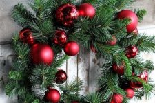 a classic holiday wreath of evergreens and glossy and matte red ornaments is a cool idea for Christmas