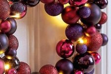 a colorful Christmas wreath amde of ornaments in fuchsia, purple, violet colors and with lights is wow