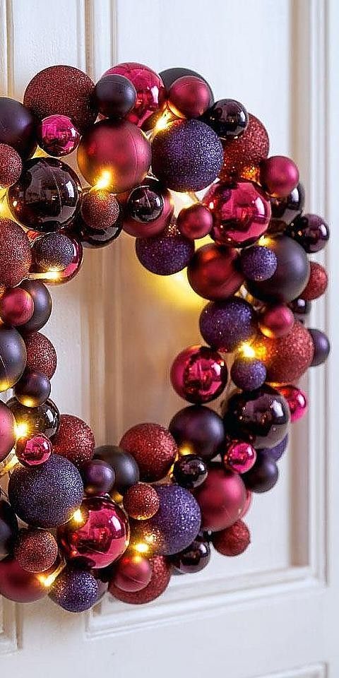 a colorful Christmas wreath amde of ornaments in fuchsia, purple, violet colors and with lights is wow