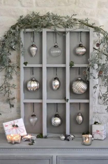a cool grey Christmas ornament display with mercury glass ornaments and greenery on top is pure elegance