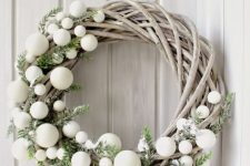 a creative whitewashed vine Christmas wreath decorated with greenery and wite ornaments is a cool Scandi decor