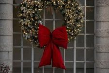 a flocked Christmas wreath with a large red bow is a cool and catchy decoration for the holidays