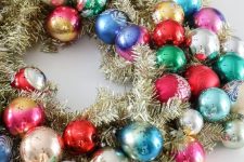 a gold tinsel Christmas wreath with colorful vintage ornaments is a super cool and catchy decoration