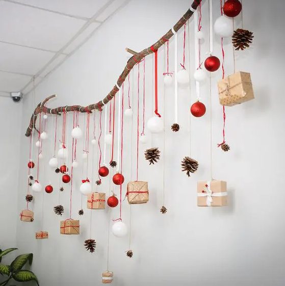 a large branch with white and red ornaments, gift boxes and pinecones is a lovely Christmas decoration to rock