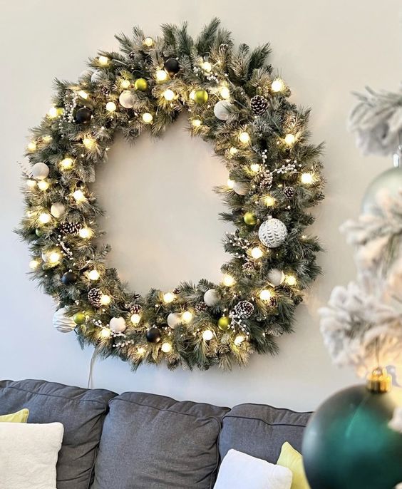 a large flocked Christmas wreath with black and white ornaments, snowy pinecones and lights