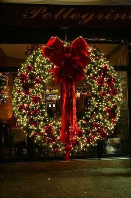 a luxurious Christmas wreath of evergreens, red ornaments and a large red bow is amazing
