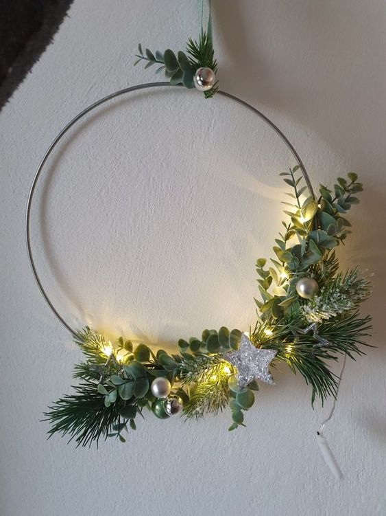 a minimal Christmas wreath with greenery and evergreens, small ornaments and a silver star is wow