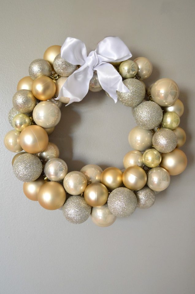 a mixed metallic ornament Christmas wreath topped with a ribbon bow is a glam and cool decor idea for the holidays