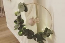 a modern Christmas wreath of an embroidery hoop, eucalyptus, mercury glass and pearl ornaments is a cool decoration