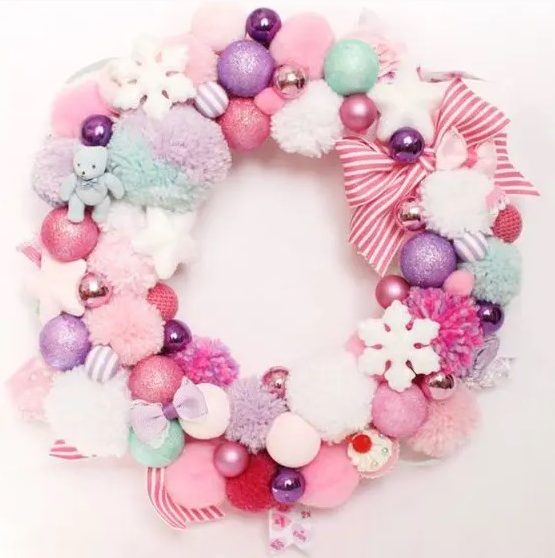 a pastel Christmas wreath of pompoms and ornaments, stars and snowflakes and striped ribbons is a pretty decoration