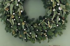a refined holiday wreath of evergreens and eucalyptus and small silver ornaments is a cool idea for Christmas