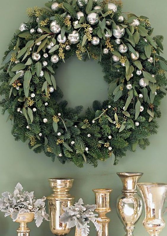 a refined holiday wreath of evergreens and eucalyptus and small silver ornaments is a cool idea for Christmas