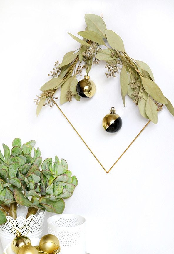 a refined modern Christmas wreath of a rhomb form, seeded euclayptus and black and gold ornaments
