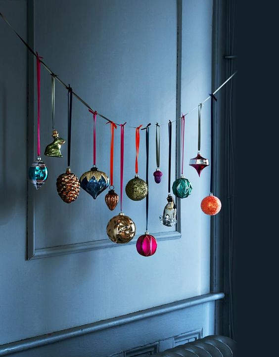 a ribbon with a whole arrangement of colorful Christmas ornaments is a cool display and a fresh decor idea