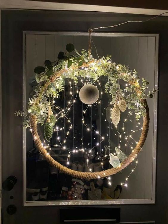 a shiny Christmas wreath with lights, greenery and white ornaments is a fresh and modern winter decoration