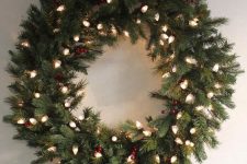 a stylish evergreen holiday wreath with red berries and lights is a catchy though laconic decoration