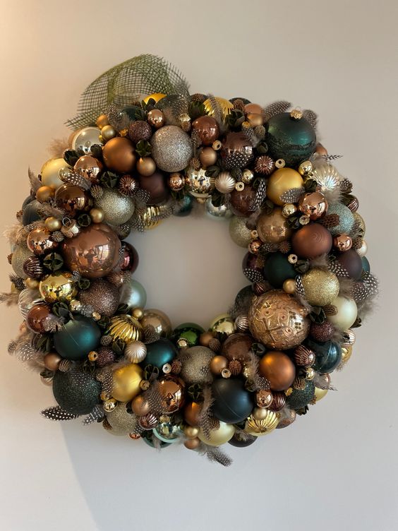 a super bright and chic Christmas wreath made completely of ornaments in gold, brown, teal and dark green looks amazing