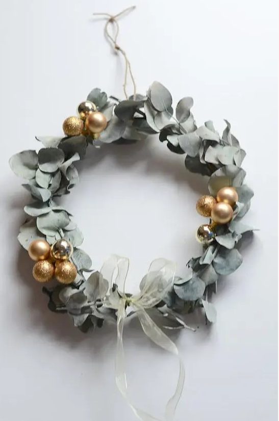 a super modern and bold eucalyptus and gold ornament wreath with a delicate ribbon bow is amazing for Christmas