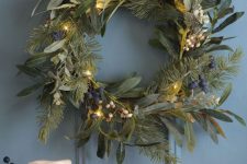 a textural greenery Christmas wreath with white and blueberries and lights is cool for natural decor