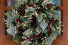 a textured Christmas wreath of leaves and evergreens, pinecones and berries plus lights is gorgeous