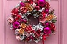 a unique flocked Christmas wreath with dried citrus, flowers and pink and silver ornaments is a super cool idea