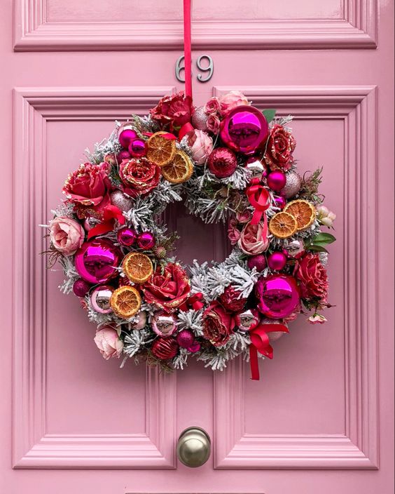 a unique flocked Christmas wreath with dried citrus, flowers and pink and silver ornaments is a super cool idea