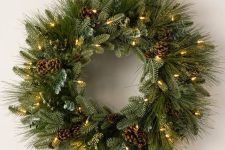 an evergreen Christmas wreath with pinecones and lights is a cool decoration for almost any space