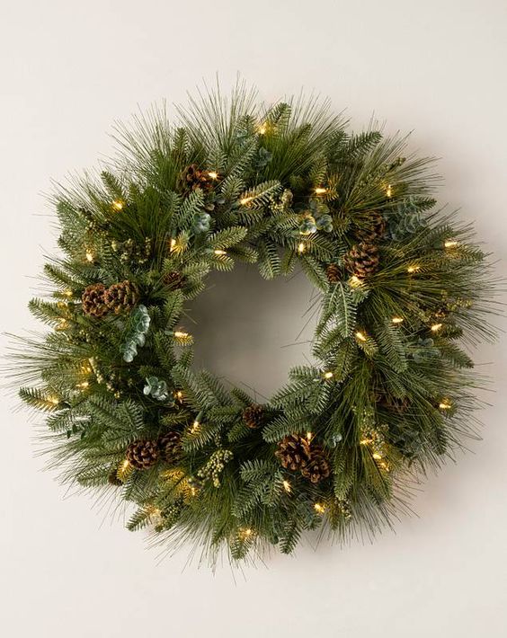 an evergreen Christmas wreath with pinecones and lights is a cool decoration for almost any space