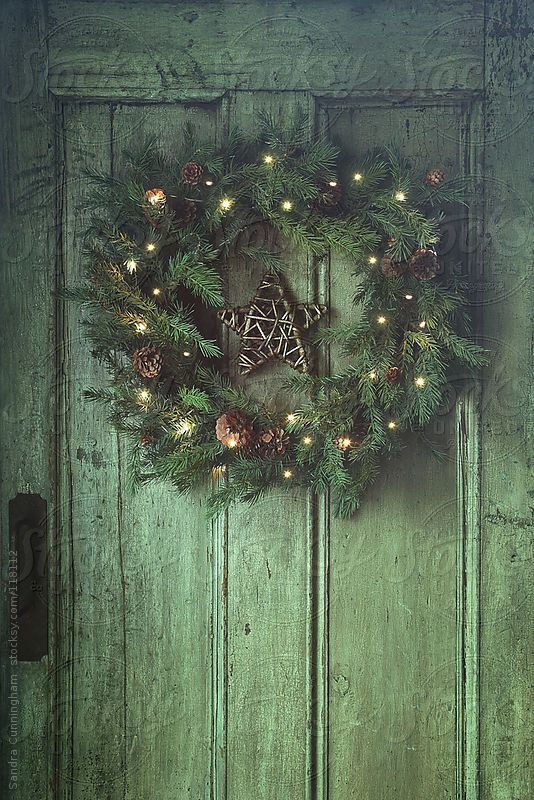 an evergreen Christmas wreath with pinecones and lights plus a twig star is a cool rustic decoration for the holidays