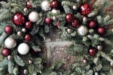 an evergreen Christmas wreath with white, silver, burgundy and grey ornaments is a chic and catchy holiday decoration