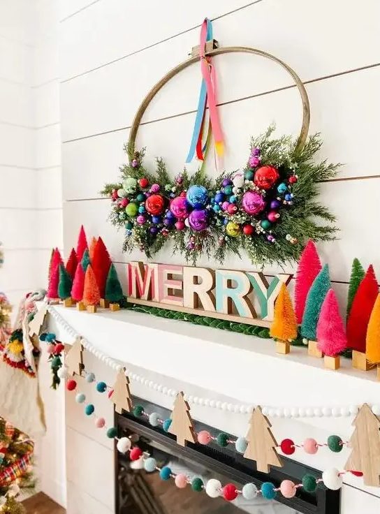 an extra bold Christmas mantel with bright bottle brush trees, letters, a wreath with ornaments and greenery, felt balls and wooden Christmas trees