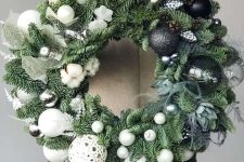 an extra bold Christmas wreath of evergreens, succulens and with black and white ornaments creating an ombre effect