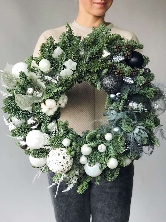 an extra bold Christmas wreath of evergreens, succulens and with black and white ornaments creating an ombre effect