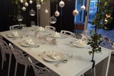 an overhead Christmas installation with lights, greenery, white and gold ornaments and clear baubles with faux snow