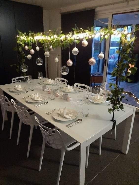 an overhead Christmas installation with lights, greenery, white and gold ornaments and clear baubles with faux snow