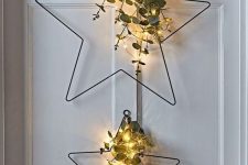 metal star-shaped Christmas wreaths with evergreens, eucalyptus and lights are a great decor idea for a Scandi or modern space