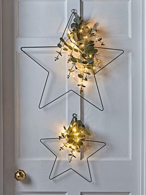 metal star-shaped Christmas wreaths with evergreens, eucalyptus and lights are a great decor idea for a Scandi or modern space