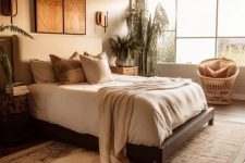 04 a lovely bedroom in earthy tones, with a dark-stained bed and neutral bedding, a rattan chair, some nightstands and potted plants