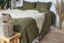 08 a boho bedroom in neutrals, with a bed done with olive green bedding, a wooden bench and woven candleholders, pampas grass, potted plants and burst mirrors