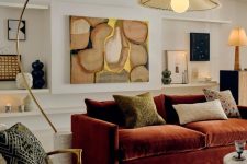 11 a sophisticated earthy tone living room with a burgundy sofa and pillows, a creamy boucle chair, a colorful rug, eye-catchy decor