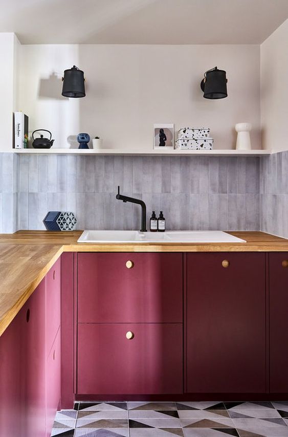 an eye-catchy berry-hued kitchen with butcherblock countertops, an open shelf and some lovely decor
