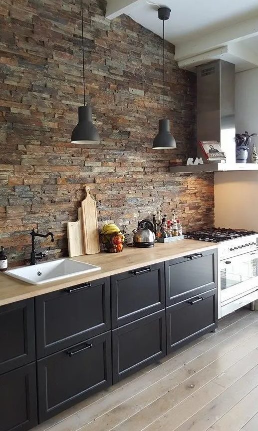 a cozy black one wall kitchen with butcherblock countertops and a faux stone wall plus pendant lamps is chic