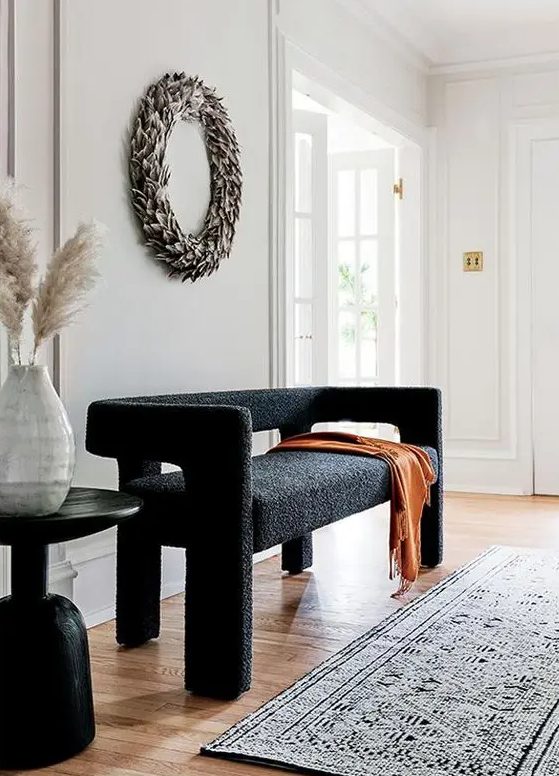 a lovely and pretty black boucle loveseat, a dried leaf wreath, a black side table for a chic and lovely space