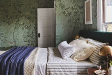 17 a vintage-inspired bedroom with green floral wallpaper, a bed with printed bedding, a rich-stained nightstand with a gilded lamp
