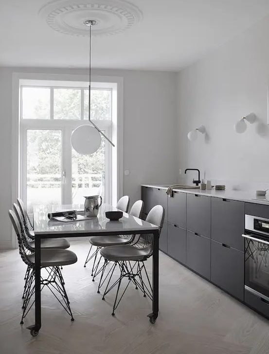 a Scandinavian black one wall kitchen with a white coutnertop and black fixtures plus some sconces and a pendant lamp
