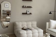 18 a neutral living room with white boucle seating furniture, a stone coffee table, small shelves and a mirror