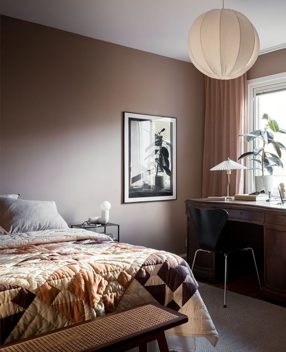 a stylish modern brown bedroom with a bed and printed bedding, a dark-stained desk and a black chair