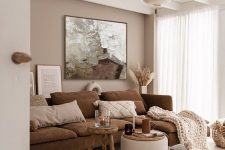 22 a lovely neutral living room with a greige accent wall, a brown sofa, a stool and a pouf, a paper lamp